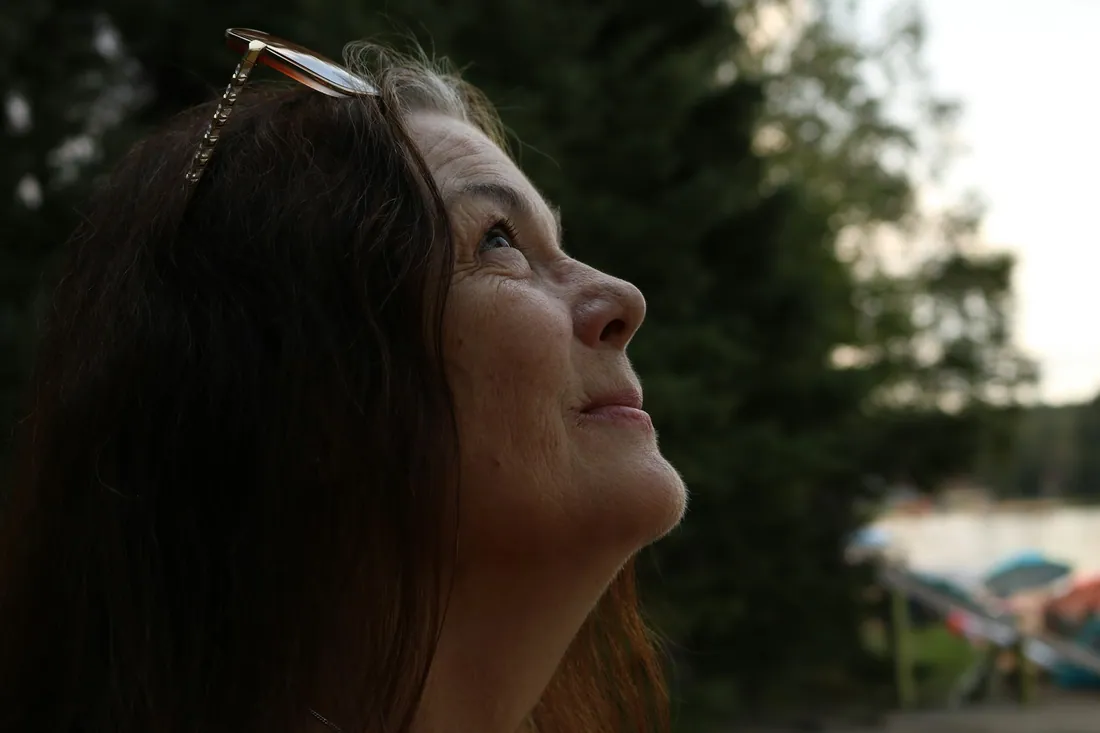 A woman in her fifties looking up into evening light