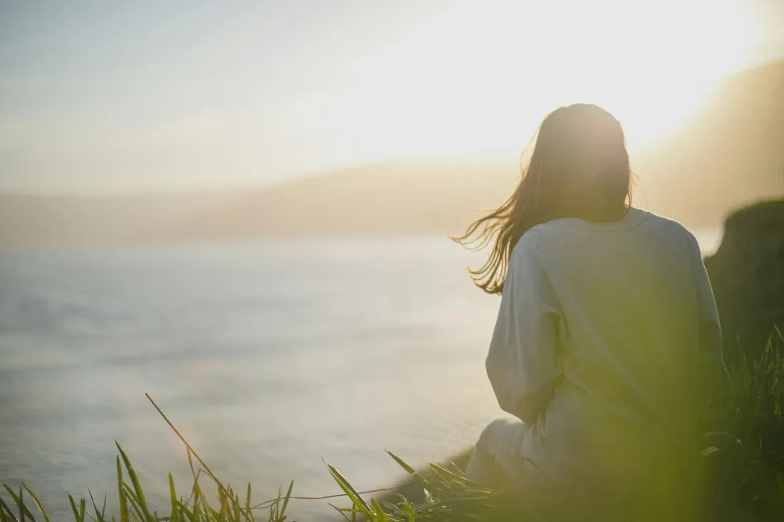 A woman sitting quietly by the sea at dusk
